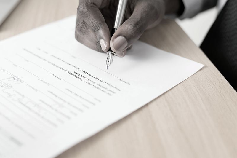 A hand signing a document at a desk